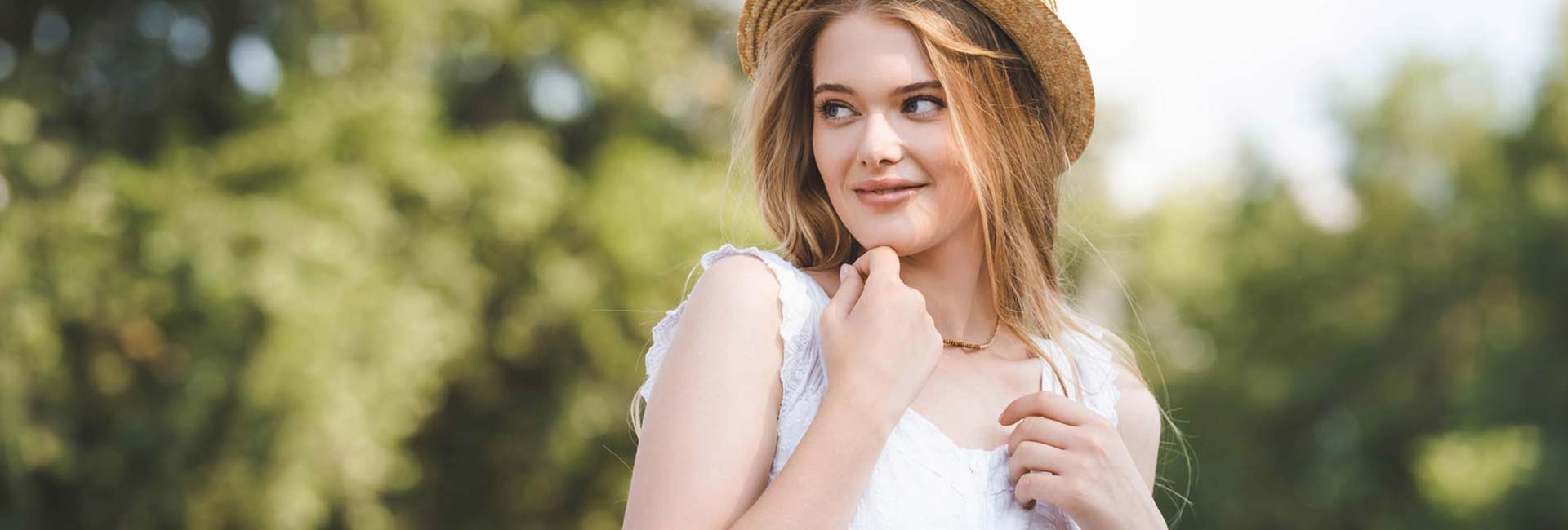 Selective focus of beautiful girl in straw hat and white dress looking away